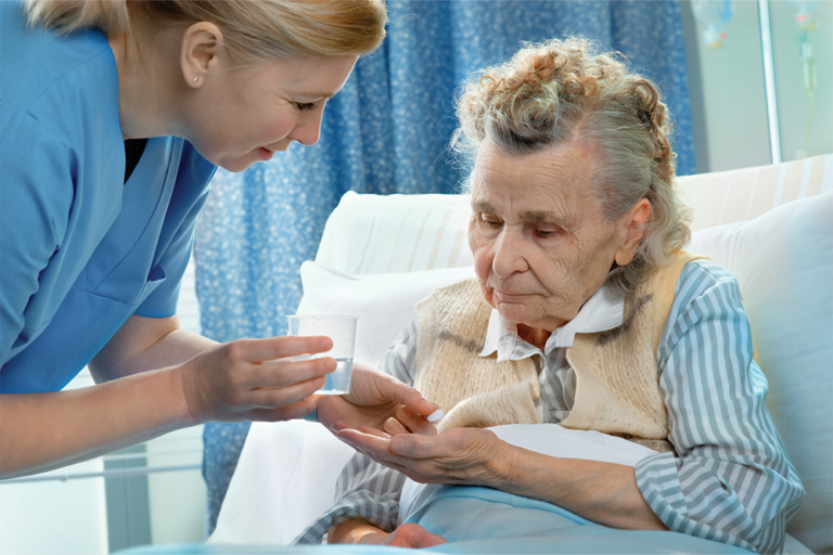 Nursing giving medication to senior woman