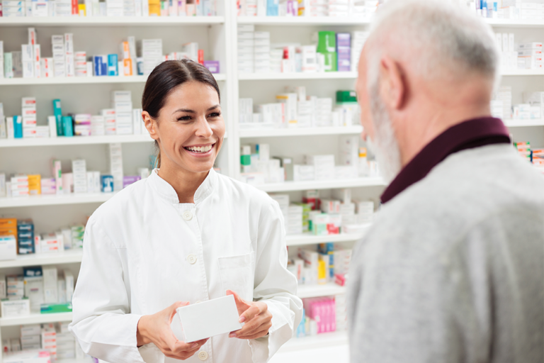 Smiling pharmacist giving medication to senior