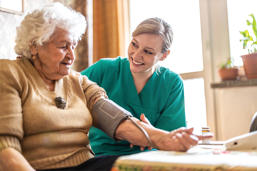 Long term care home worker checking senior woman's blood pressure