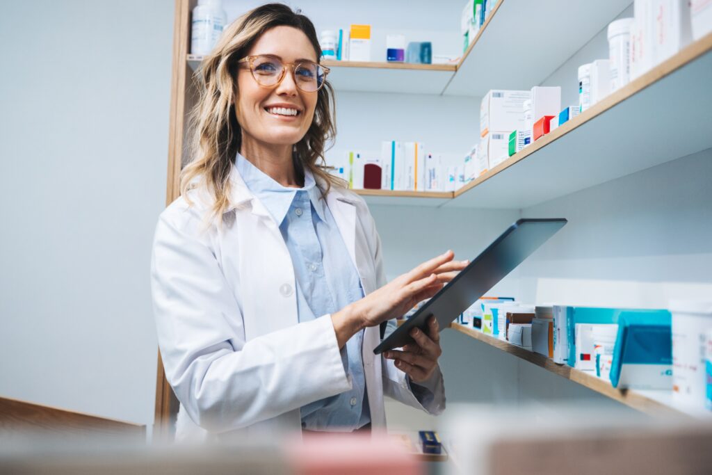 Happy female pharmacist using a tablet.