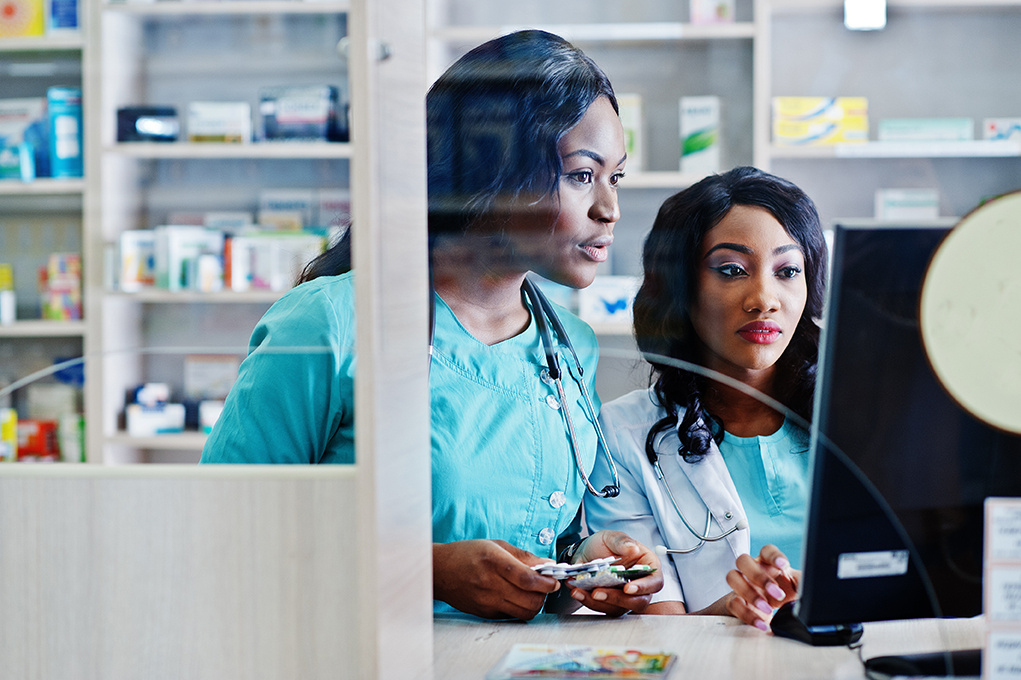 Two concerned looking pharmacists looking closely at computer