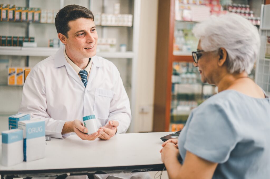 Male pharmacist discussing medication with elderly patient.